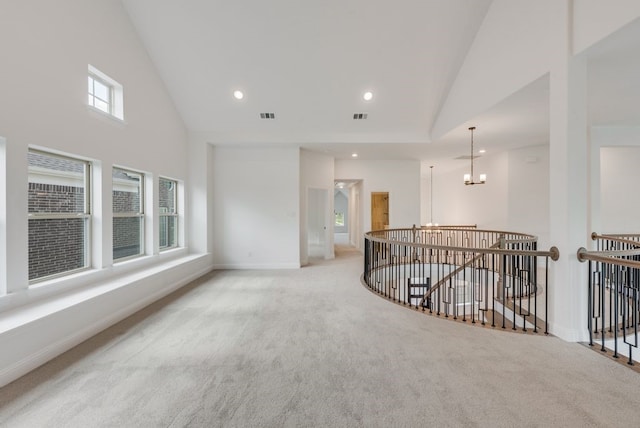 interior space with light carpet, high vaulted ceiling, and a notable chandelier