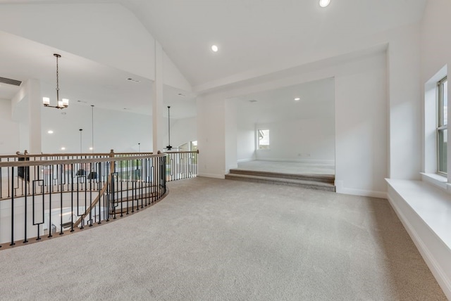 unfurnished room featuring an inviting chandelier, light colored carpet, and high vaulted ceiling