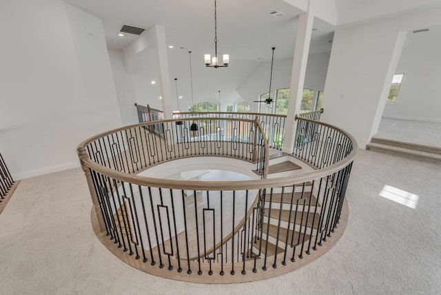 staircase featuring carpet flooring, ceiling fan with notable chandelier, and a towering ceiling