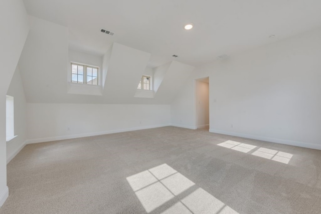 bonus room with light carpet and vaulted ceiling