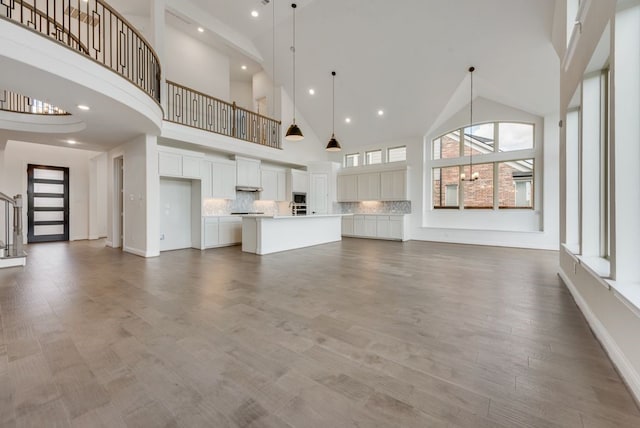 unfurnished living room featuring high vaulted ceiling and wood-type flooring