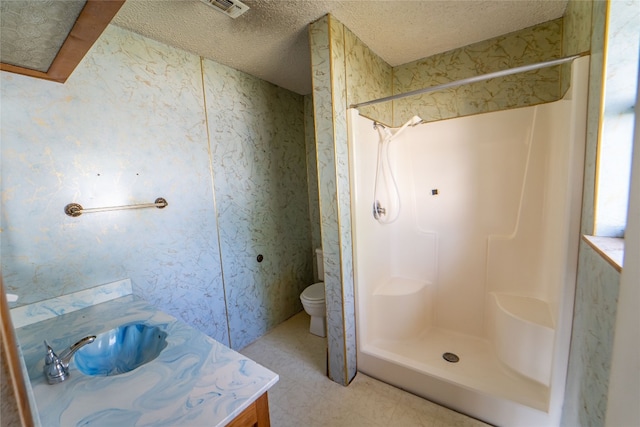 bathroom featuring a shower, vanity, tile flooring, toilet, and a textured ceiling