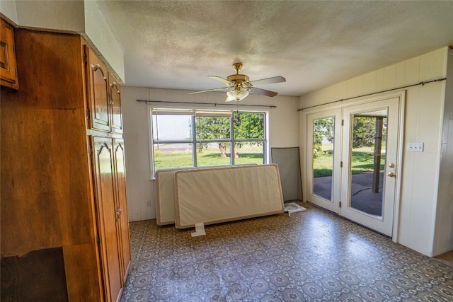 interior space with a textured ceiling, ceiling fan, access to exterior, and tile flooring