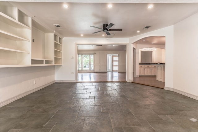 unfurnished living room with built in features, ceiling fan, lofted ceiling with beams, a fireplace, and hardwood / wood-style floors