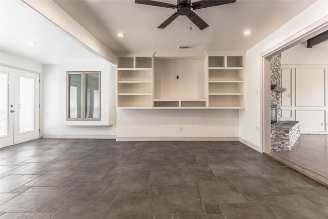 unfurnished living room featuring ceiling fan and dark tile floors