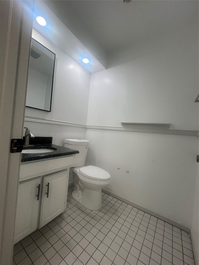 bathroom featuring tile flooring, vanity, and toilet