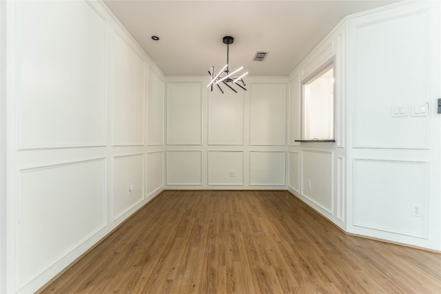 spare room with light hardwood / wood-style flooring and an inviting chandelier