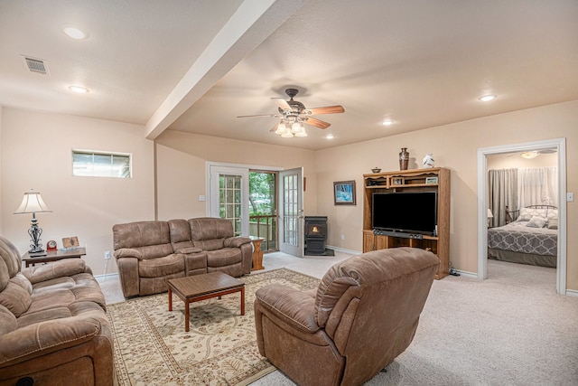 living room featuring carpet flooring, ceiling fan, and a wood stove