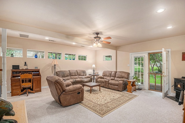 carpeted living room featuring ceiling fan and a wood stove