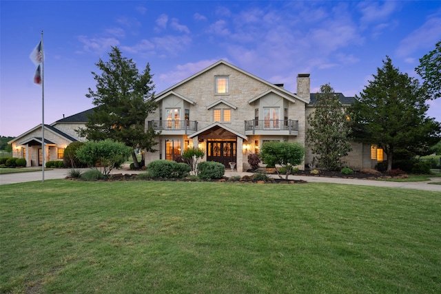 view of front of property with a balcony and a yard