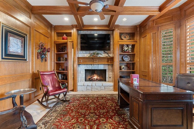 office featuring a fireplace, wooden walls, built in features, ceiling fan, and beam ceiling