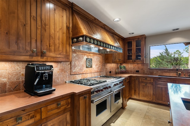 kitchen featuring custom exhaust hood, decorative backsplash, sink, and double oven range