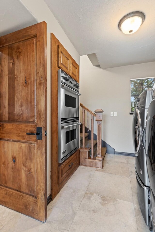 kitchen with stainless steel double oven, a textured ceiling, and washing machine and clothes dryer