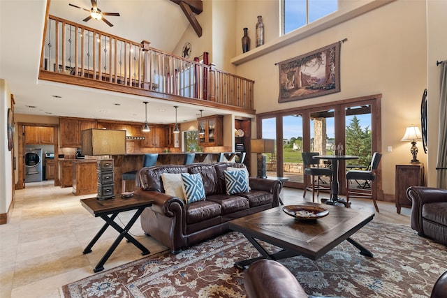 tiled living room with a towering ceiling, washer / dryer, and ceiling fan