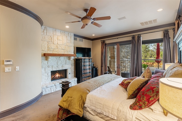 bedroom with ceiling fan, ornamental molding, and a stone fireplace