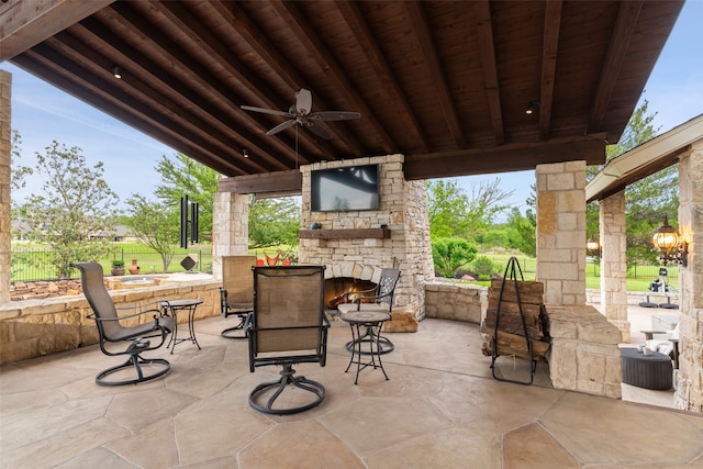 view of patio with an outdoor stone fireplace and ceiling fan