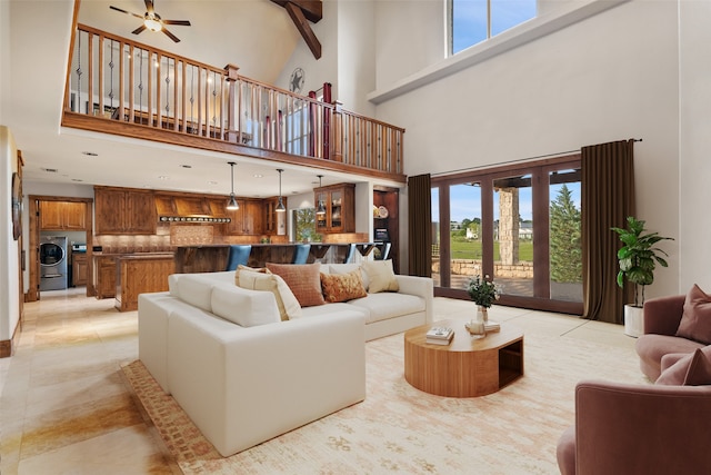 living room with washer / clothes dryer, ceiling fan, light tile patterned floors, and a towering ceiling