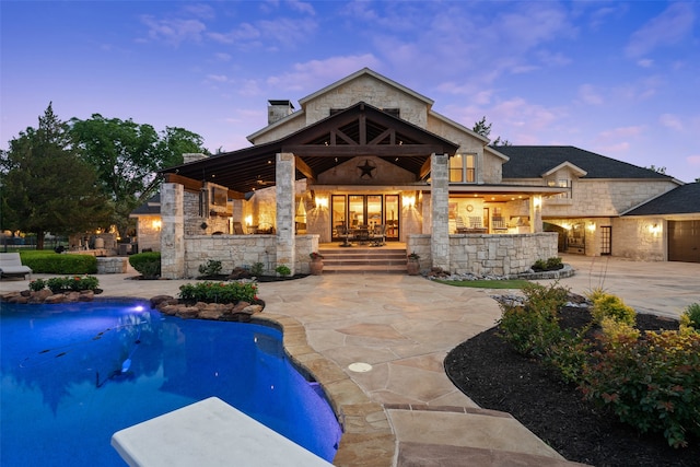 pool at dusk with a patio area and french doors