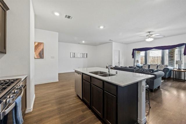 kitchen with a kitchen island with sink, dark hardwood / wood-style floors, appliances with stainless steel finishes, sink, and ceiling fan