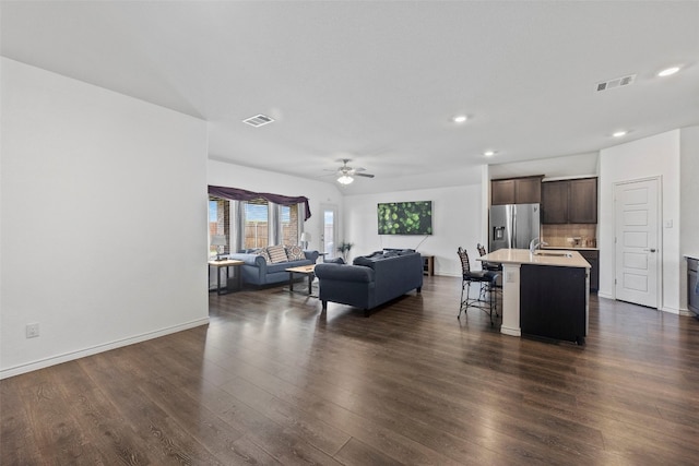 living room with sink, ceiling fan, and dark wood-type flooring