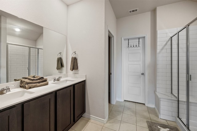 bathroom featuring a shower with shower door, double vanity, and tile flooring