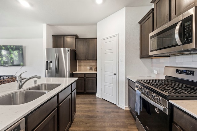 kitchen featuring dark hardwood / wood-style floors, backsplash, appliances with stainless steel finishes, sink, and light stone counters