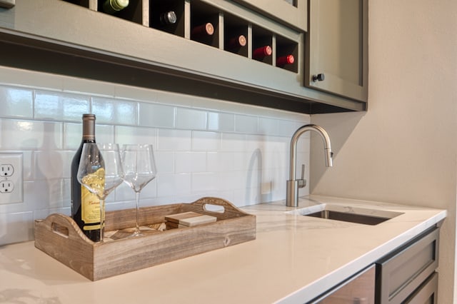 kitchen with decorative backsplash, sink, and light stone counters