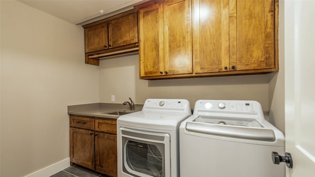 laundry room with cabinets, dark tile patterned floors, washer and dryer, and sink