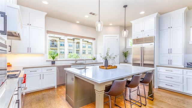 kitchen featuring a healthy amount of sunlight, white cabinetry, a breakfast bar area, and an island with sink