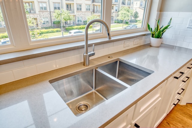 details featuring white cabinets, sink, and decorative backsplash