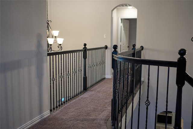 staircase with a notable chandelier and carpet floors