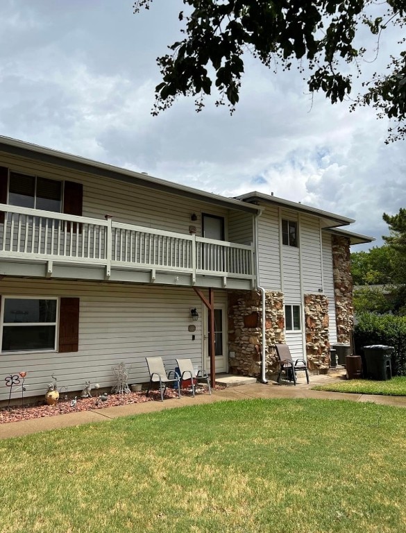 back of house featuring a balcony and a lawn