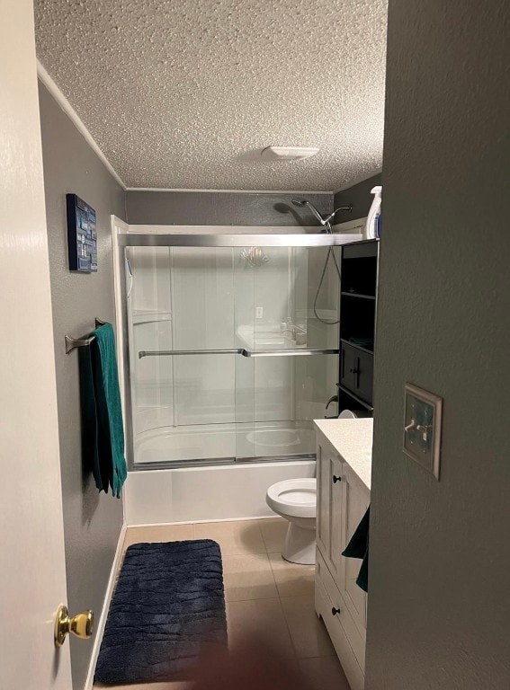 full bathroom featuring tile floors, vanity, bath / shower combo with glass door, toilet, and a textured ceiling