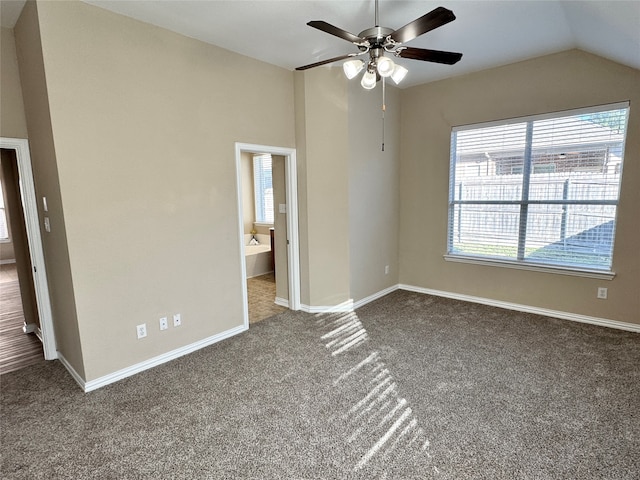 unfurnished bedroom with ceiling fan, vaulted ceiling, and dark colored carpet