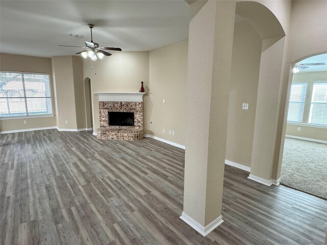 unfurnished living room with ceiling fan, dark hardwood / wood-style floors, and a brick fireplace