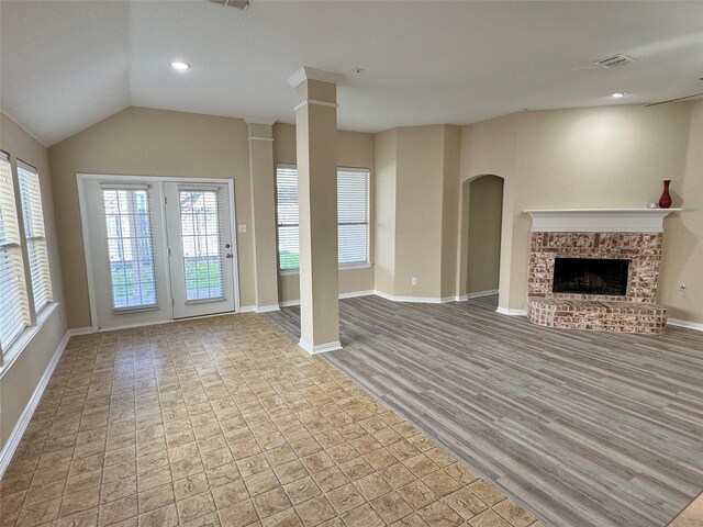 unfurnished living room with light hardwood / wood-style flooring, lofted ceiling, and a brick fireplace