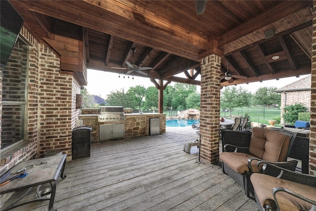 deck featuring grilling area, an outdoor kitchen, a fenced in pool, ceiling fan, and an outdoor hangout area