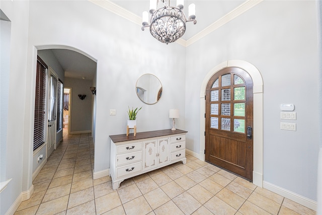 foyer entrance featuring a chandelier, ornamental molding, and light tile floors