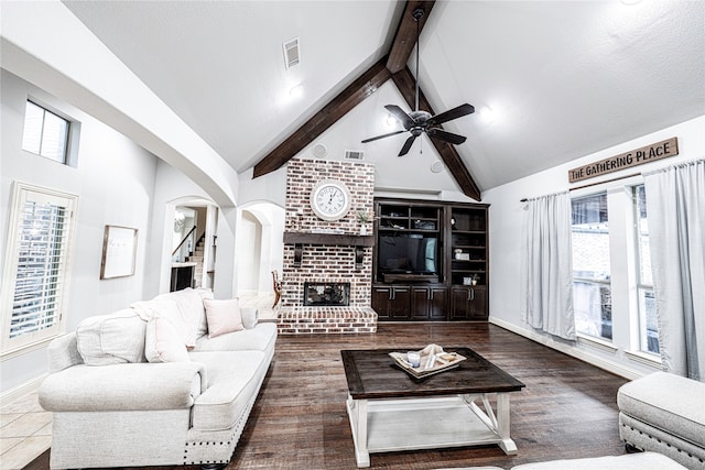 living room with ceiling fan, dark hardwood / wood-style flooring, brick wall, and a brick fireplace