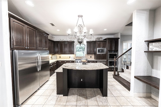 kitchen with decorative light fixtures, light tile flooring, dark brown cabinets, stainless steel appliances, and a kitchen island