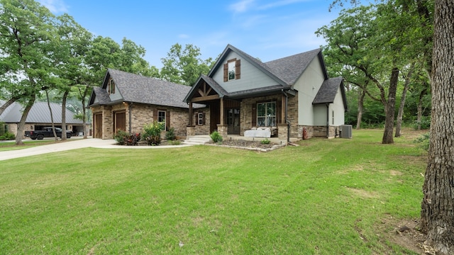 view of front facade with a front yard, a garage, central air condition unit, and covered porch