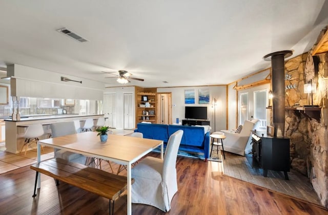 dining room featuring dark hardwood / wood-style flooring, ceiling fan, and a wood stove