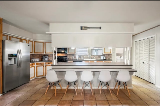 kitchen featuring light tile floors, stainless steel refrigerator with ice dispenser, and range