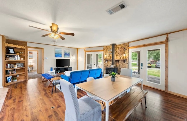 dining space with french doors, a wood stove, ceiling fan, and hardwood / wood-style floors