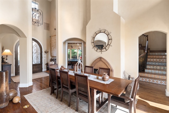 dining space featuring a chandelier, wood-type flooring, and a high ceiling