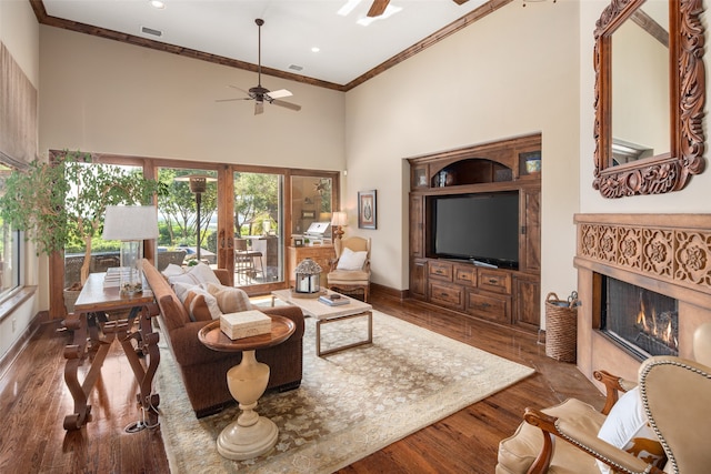 living room featuring french doors, ceiling fan, crown molding, dark wood-type flooring, and a high ceiling