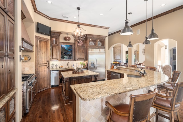 kitchen featuring pendant lighting, high quality appliances, a spacious island, sink, and a chandelier