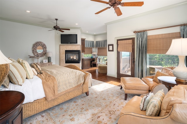 bedroom featuring ceiling fan, wood-type flooring, ornamental molding, and a tile fireplace