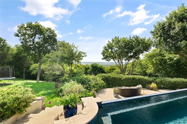 view of swimming pool with a patio, a trampoline, and a lawn