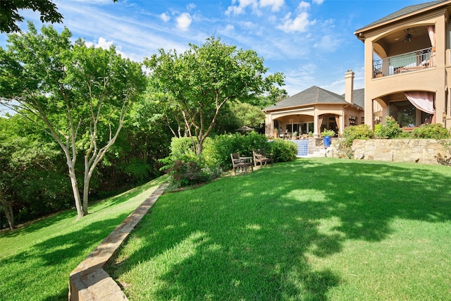 view of yard with a balcony and ceiling fan